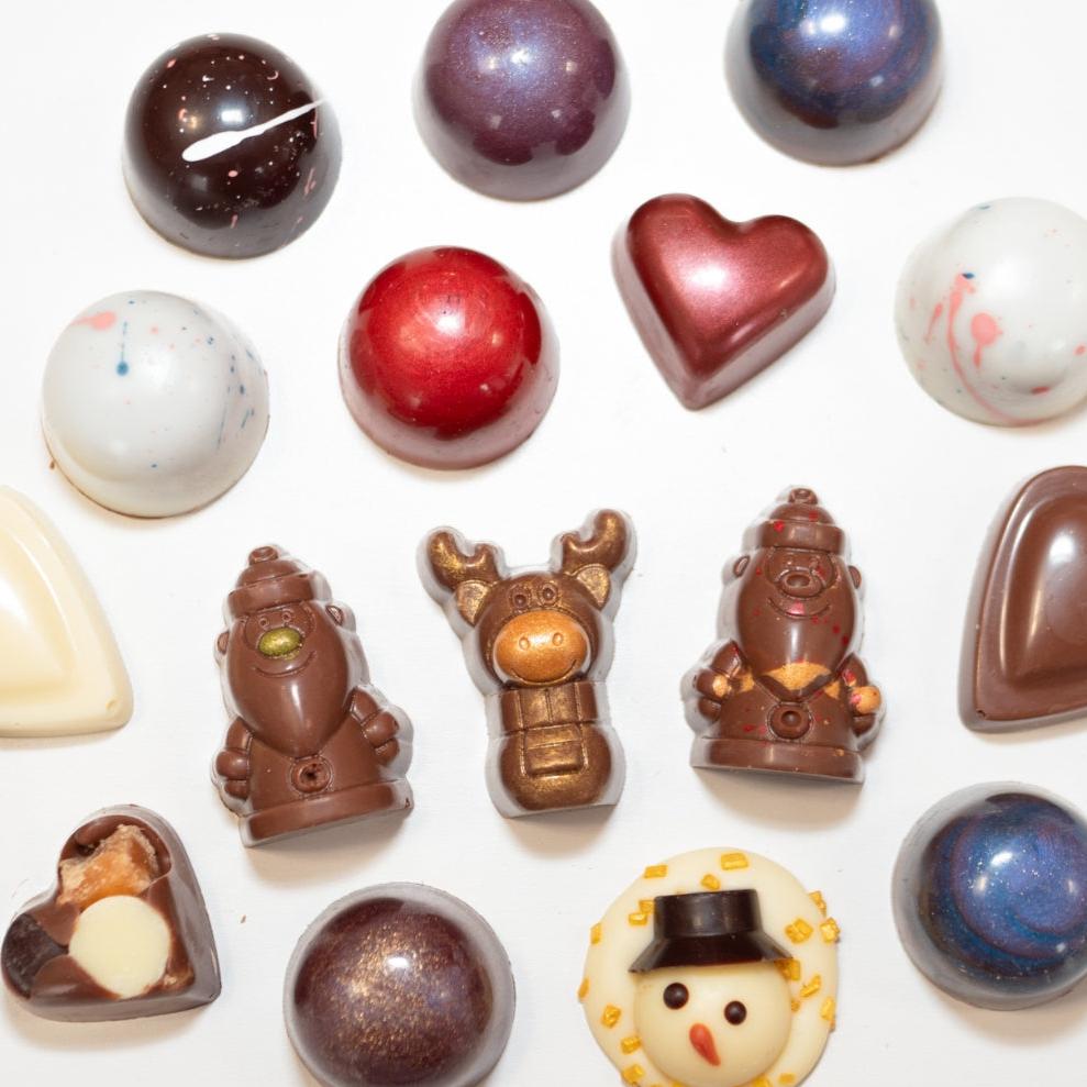 Assorted festive chocolates from La Chocolatrice Advent Calendar including Santa, reindeer, snowman, and a variety of decorative bonbons in holiday colours.