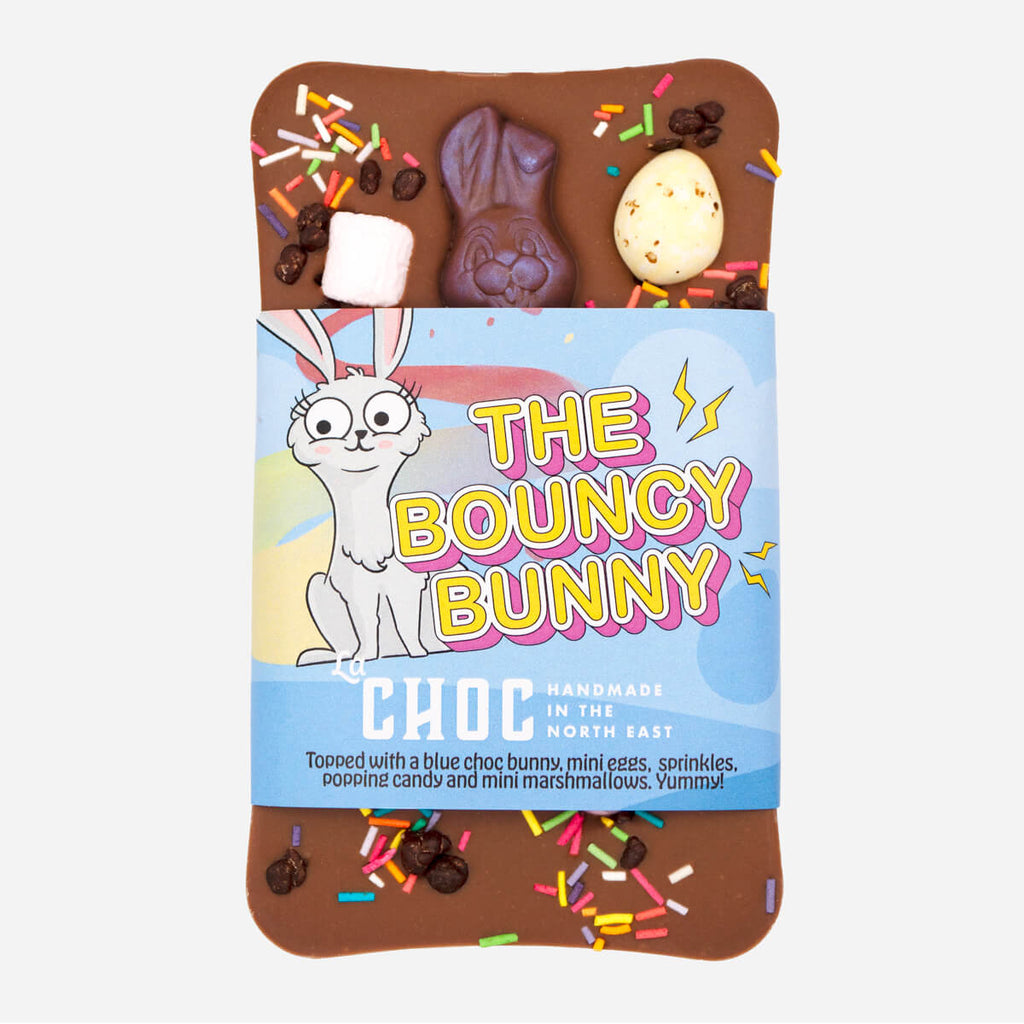 The Bouncy Bunny chocolate bar by La Choc, decorated with a blue chocolate bunny, mini eggs, sprinkles, popping candy, and marshmallows.